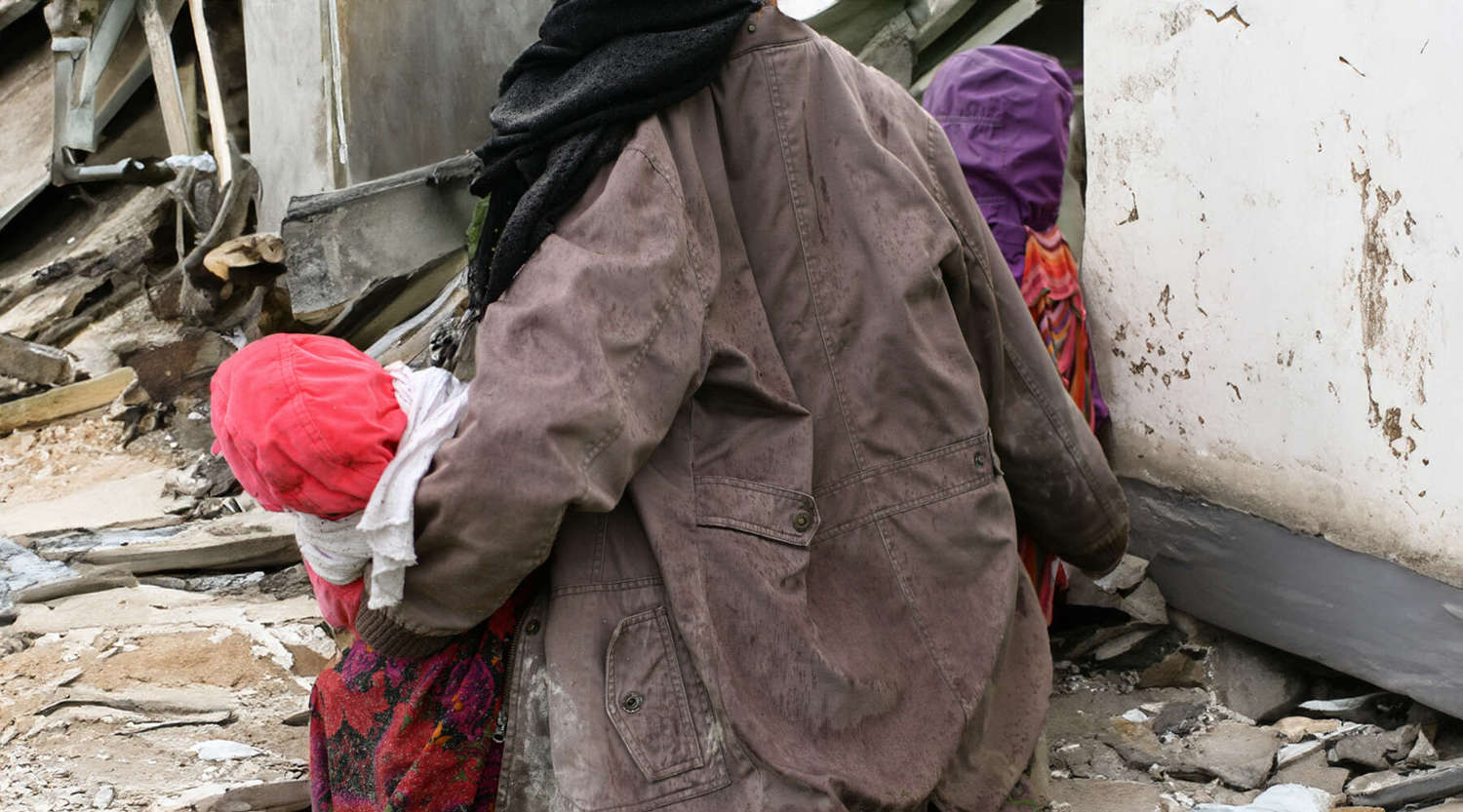 Mother with children near a destroyed house