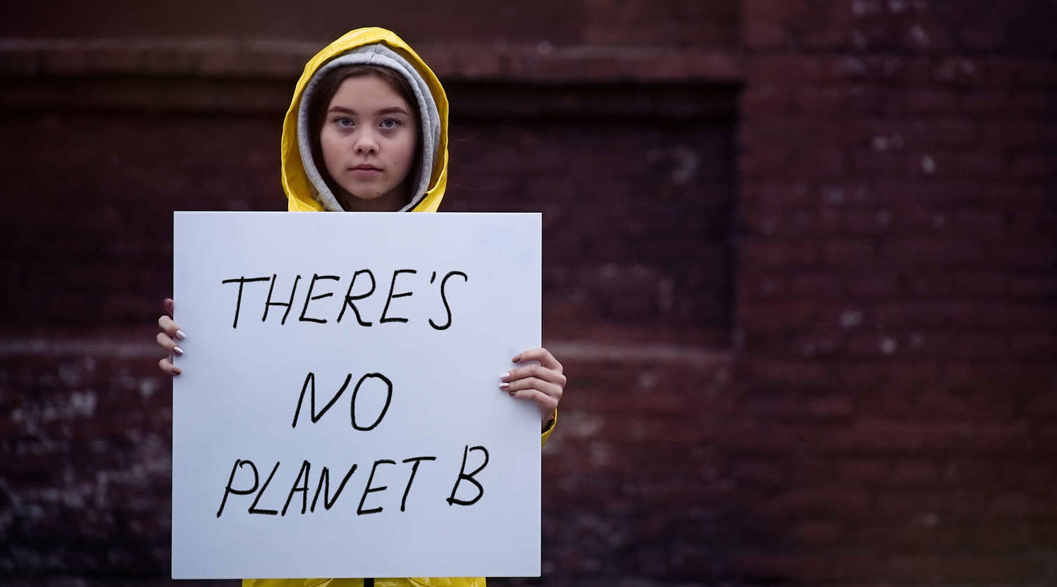 child holding 'there's no planet b' sign